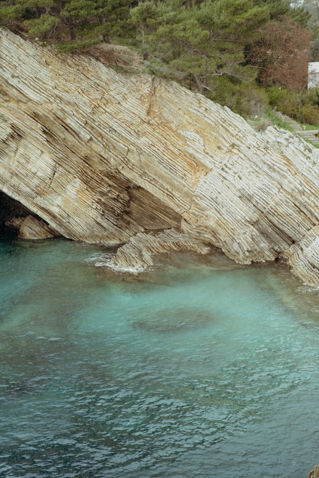 Turquoise water washing over the rocky Adriatic coastline below Mahakala Center
